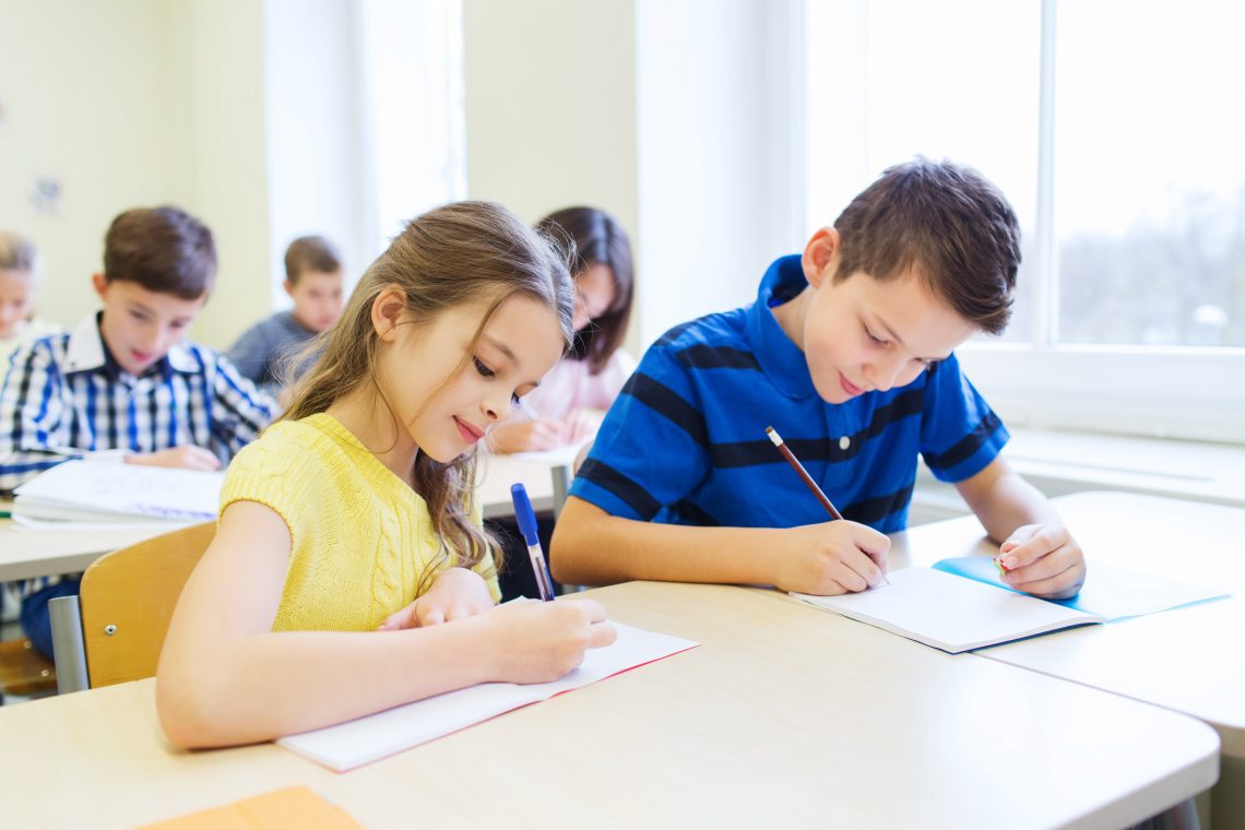 group of school kids writing test in classroom