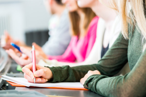 College students making lesson notes in university auditorium