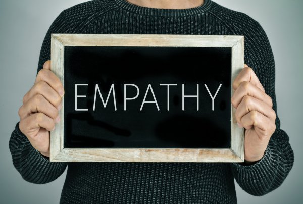 closeup of a young caucasian man showing a chalkboard with the text empathy written in it