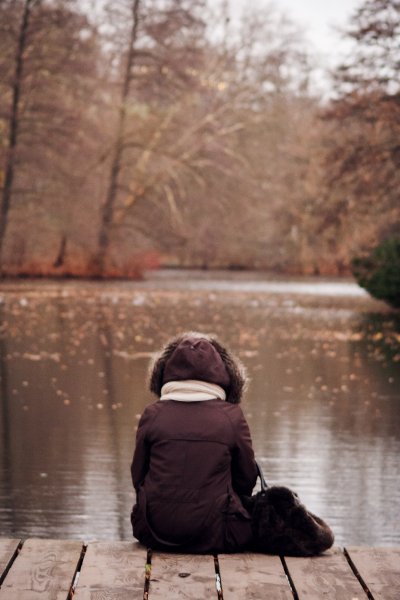 Frau sitzt alleine am See