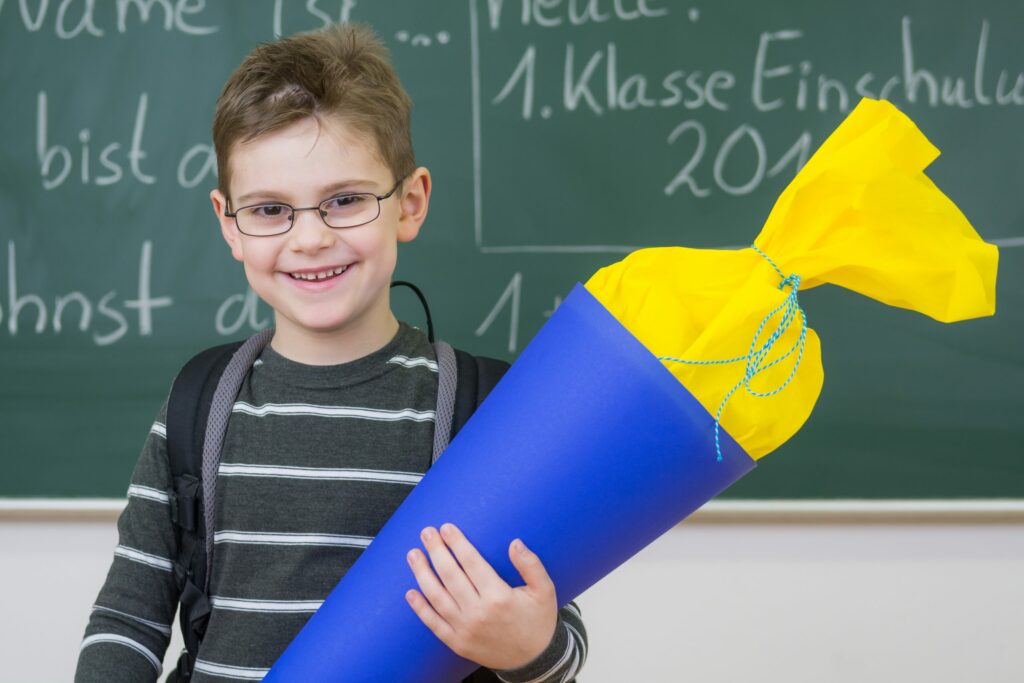 Schulanfang mit Diabetes: Was Familien jetzt beachten müssen | Ein Junge steht mit seiner Schultüte vor einer Tafel.