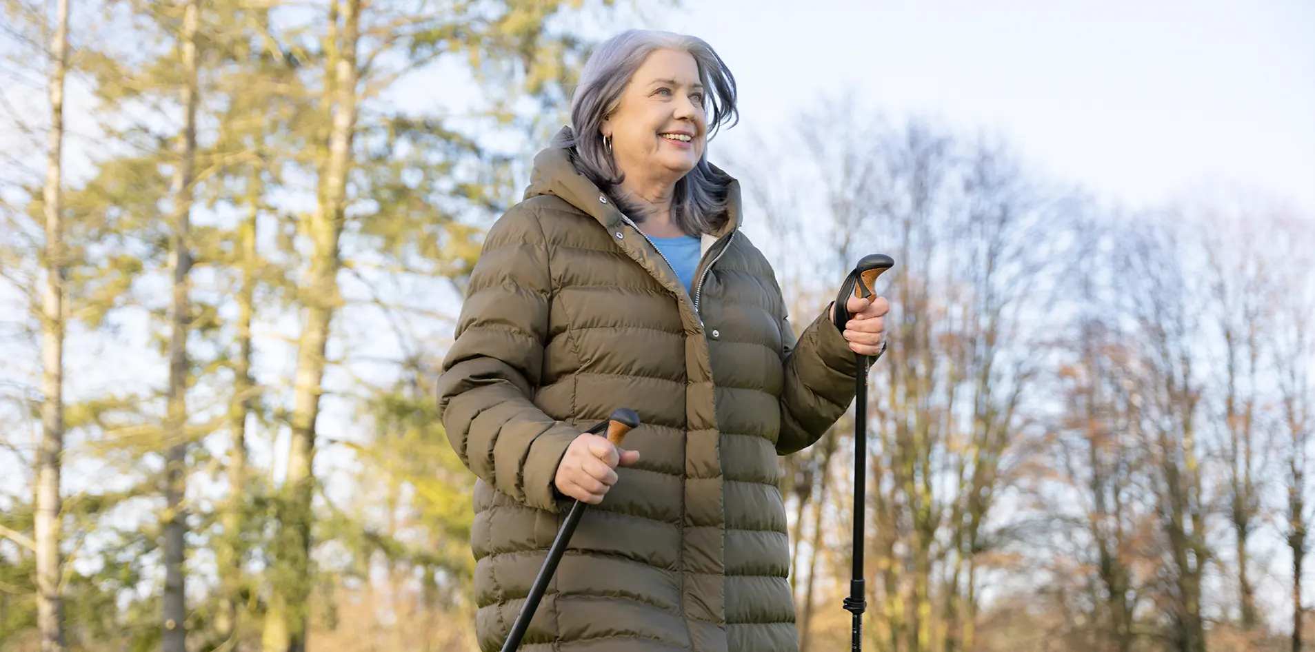 Eine Frau lauft mit Walking-Stöcken durch den Wald