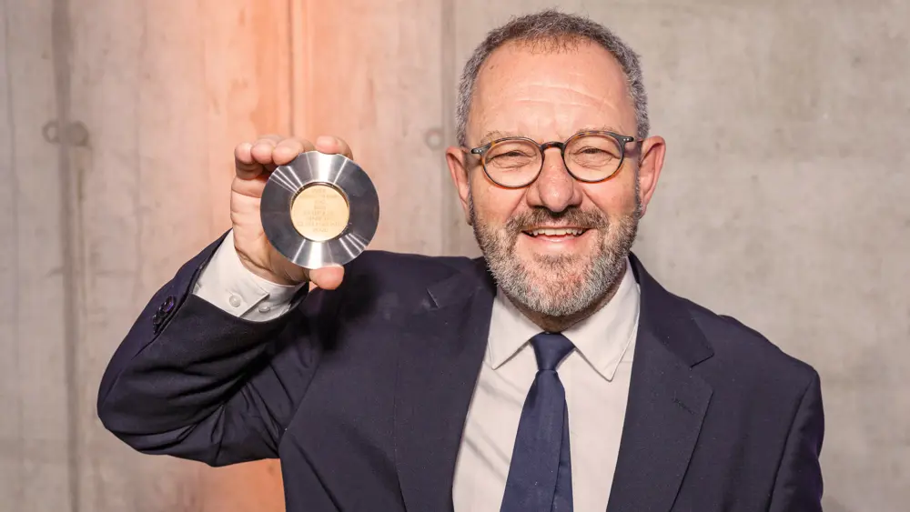 Prof. Dr. Michele Solimena hält mit einem breiten Lächeln die ihm verliehene Paul-Langerhans-Medaille nach oben.