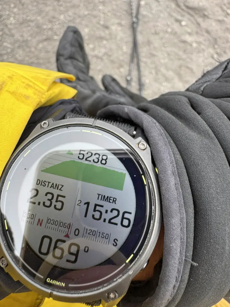 Nahaufnahme einer Outdoor-Sportuhr mit angezeigten Tourdaten wie Distanz, Zeit und Höhenangabe.