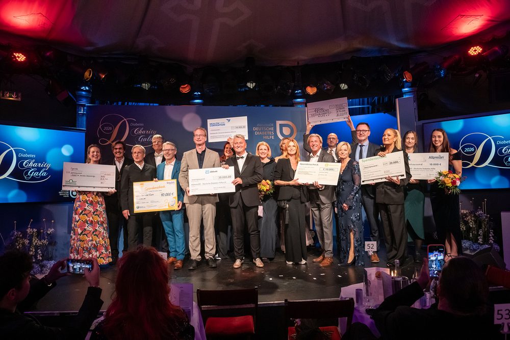 Eine große Gruppe von Vertreterinnen und Vertretern der Industrie steht zusammen mit den prominenten Gästen auf der Bühne der Diabetes-Charity-Gala und hält zahlreiche Spendenschecks in die Höhe.
