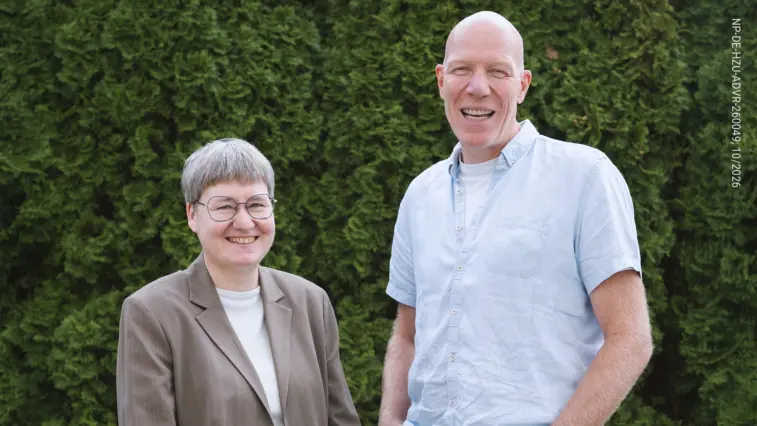 Dr. med. Katrin Kraatz (links) und Dr. med. Dietrich Tews stehen lächelnd vor einer grünen Hecke.