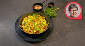 Lauch-Pfanne mit Penne und Tofu in einer dunklen Schale, daneben Basilikum und kleine Schälchen mit Gewürzen, oben rechts ein rundes Porträt von Dr. med. Katrin Kraatz.