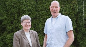 Dr. med. Katrin Kraatz (links) und Dr. med. Dietrich Tews stehen lächelnd vor einer grünen Hecke.