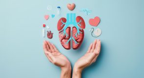 Zwei geöffnete Hände halten eine stilisierte Darstellung von Lunge und weiteren Organen, umgeben von medizinischen Symbolen wie Herzen, Tabletten und einem EKG.